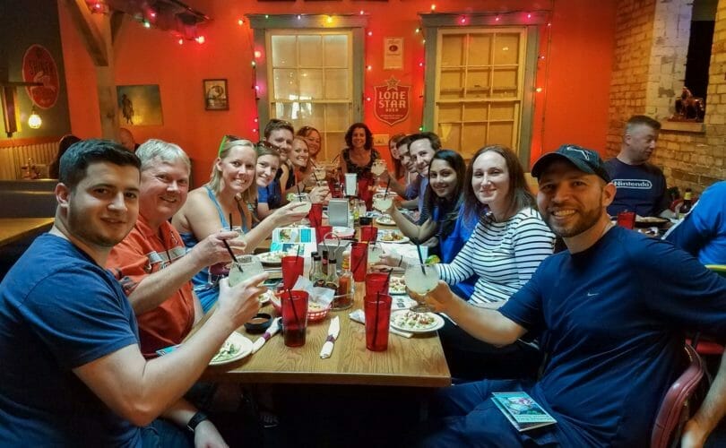 Food and drink tour guests smiling and dining at long table