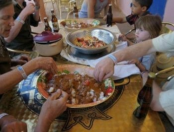 Group communal eating out of a large bowl at table