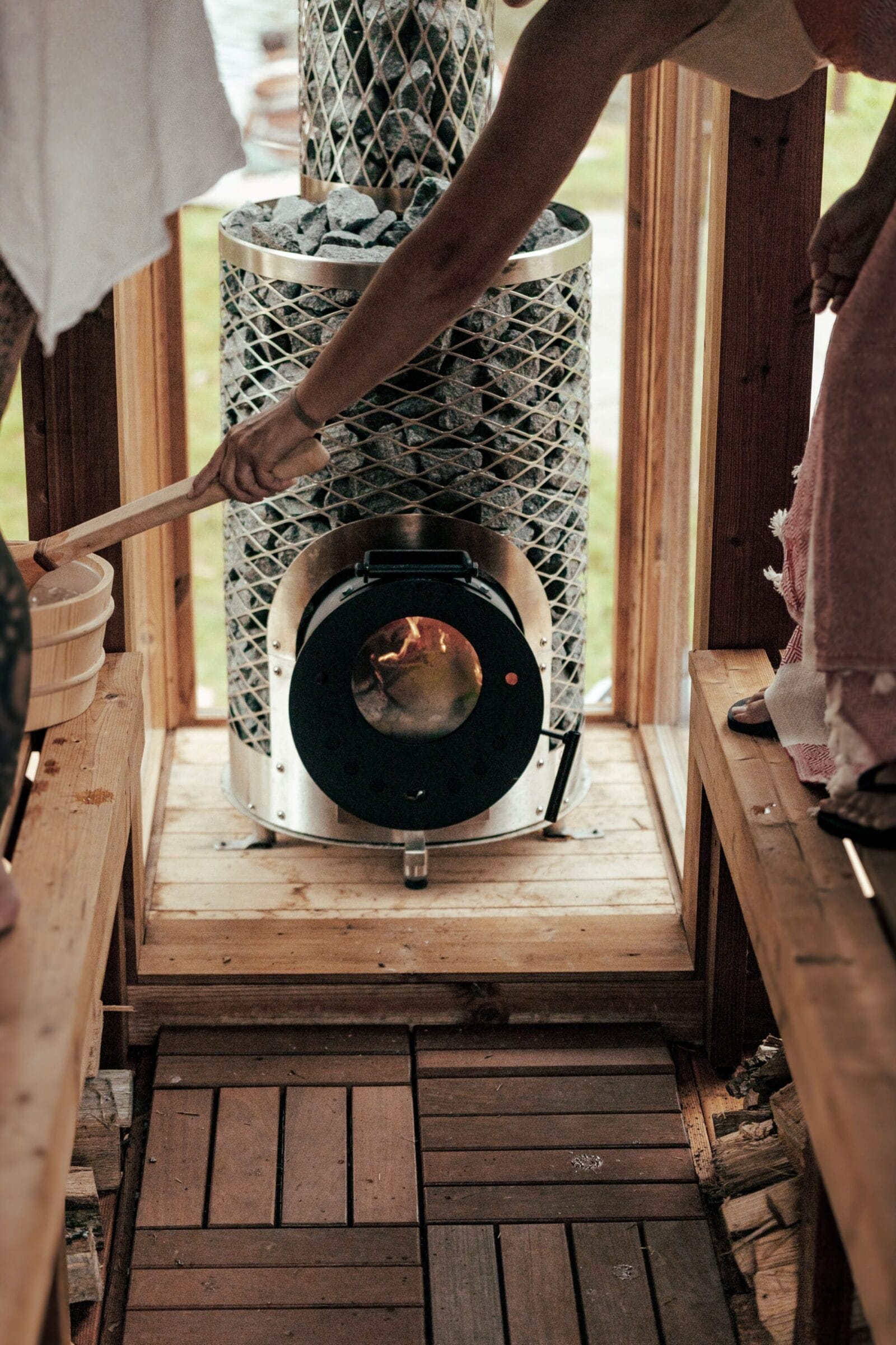 Woman pouring water on a fire in a wood sauna