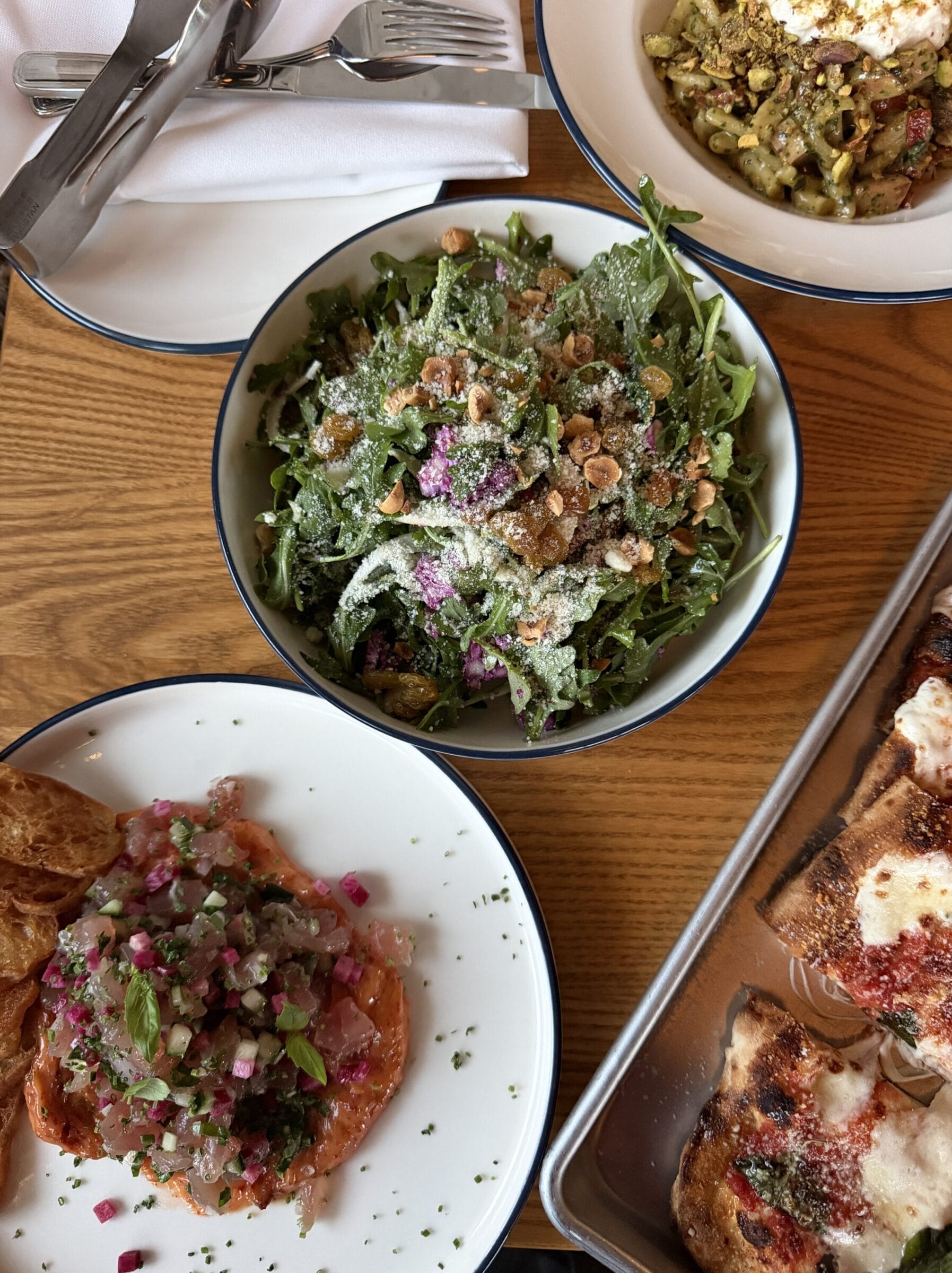 Spread of Italian dishes including pasta pizza and salad from Osteria Novella