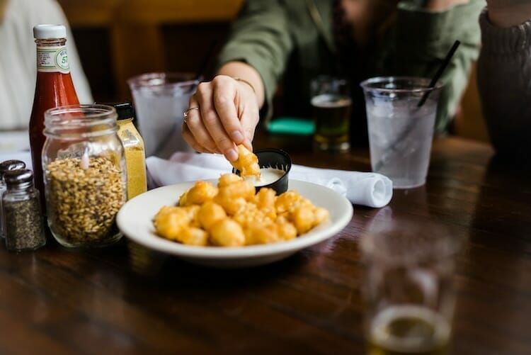 Guest dipping cheese curds on food tour