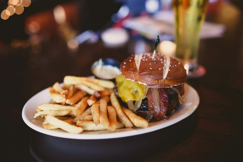 Plate of pretzel bun burger and fries from Around the Square food tour