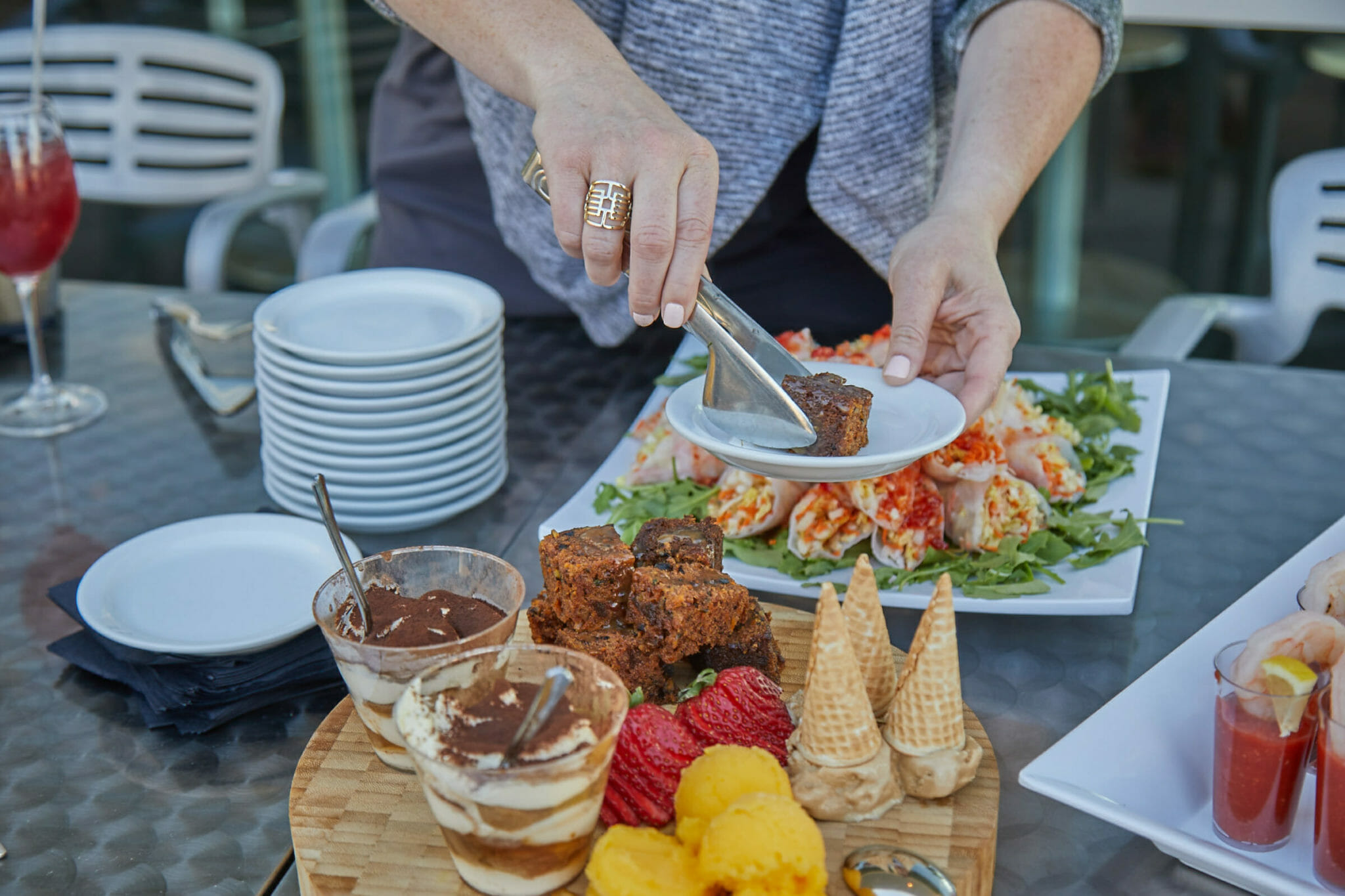 Woman dishing up plate at table of desserts & appetizers from Fare & Square food tour